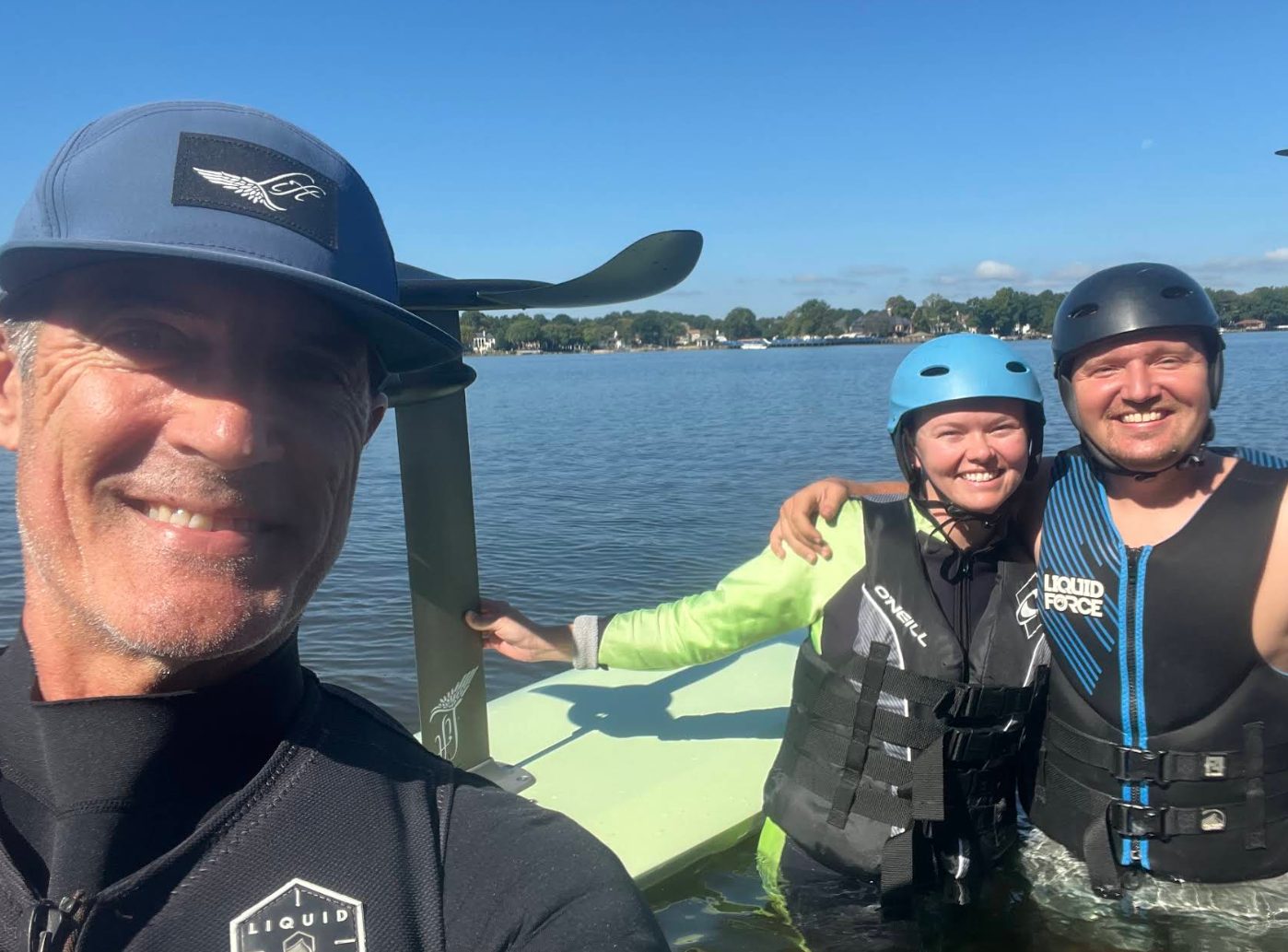 Dan posing with two smiling riders next to an eFoil on the lake